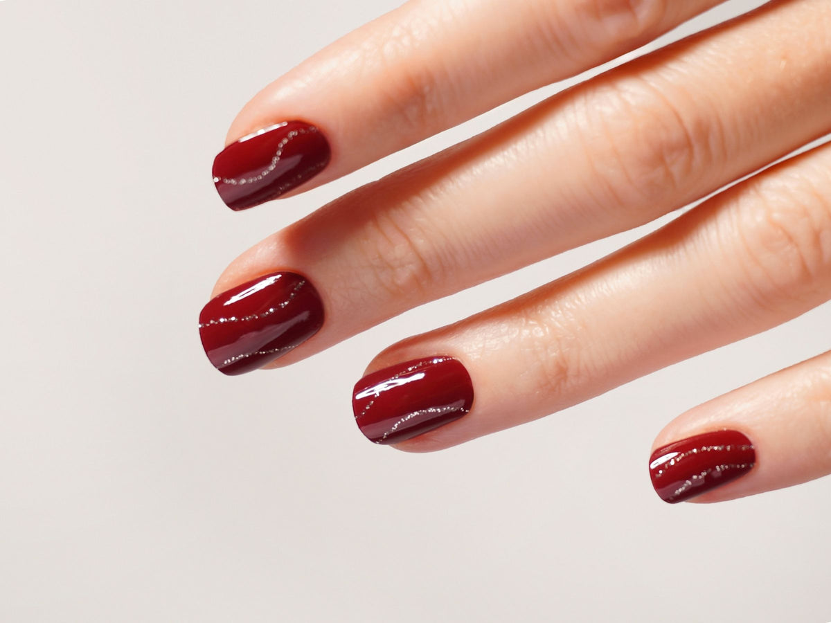 Weihnachtliche rote Nägel mit silbernen Glitzerstreifen.